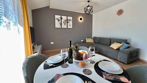 Een eethoek met een ronde tafel voor vier personen, een grijze bank en een wanddecoratie.