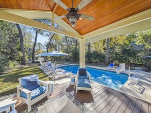 A covered outdoor swimming pool area with lounge chairs, a ceiling fan, and a sign indicating the direction to the beach. - Beautiful Palmetto Dunes Home w/ Pool and Spa (Hilton Head Island)