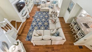 Amplia sala de estar con un sofá grande, un tapete estampado y una cocina con taburetes de bar.