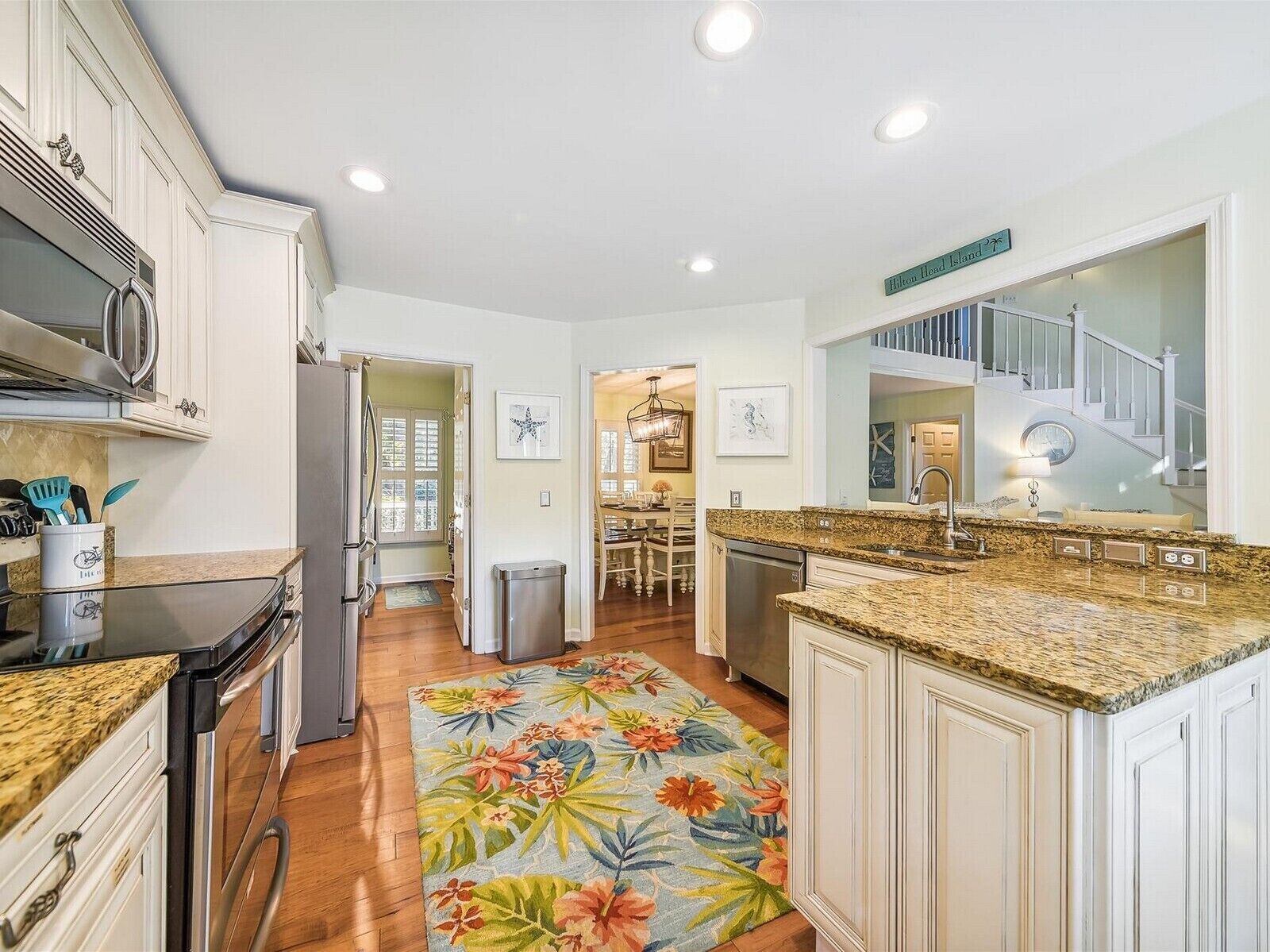 A modern kitchen with white cabinetry, granite countertops, and a central island. There is a dining area visible in the background.