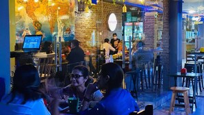 A restaurant with a brick wall, a map mural, and outdoor seating. - Encantador Dpto en Garzota norte  (Guayaquil)