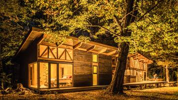 A modern cabin with a glass facade, wooden exterior, and a deck area.