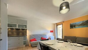 A compact living space with a dining area, kitchenette, and a sofa.