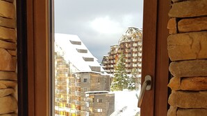 A window with a view of a snowy mountain and a building with a sloped roof. - Studio 4 P ideally located with magnificent view (Morzine)