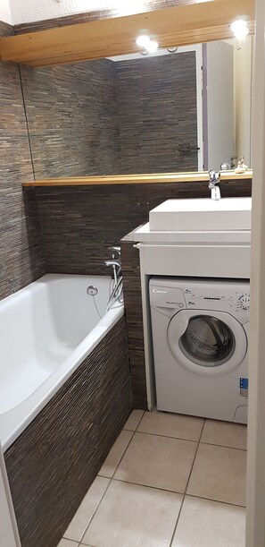 Un baño con bañera, lavamanos y lavadora.