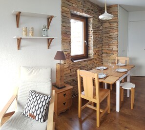 Un comedor acogedor con pared de piedra, mobiliario de madera y ventana con vistas.