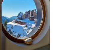 A round window with a view of a snowy mountain landscape and buildings. - Studio 4 P ideally located with magnificent view (Morzine)