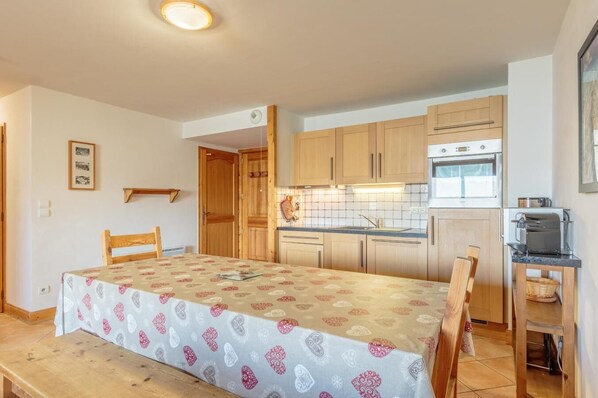 A compact kitchen with wooden cabinets, a built-in oven, and a dining area with a table set for two.