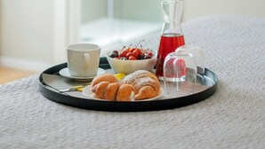 A tray with pastries, a cup, a bowl of fruit, and a bottle of water on a textured surface. - moris  (Palermo)