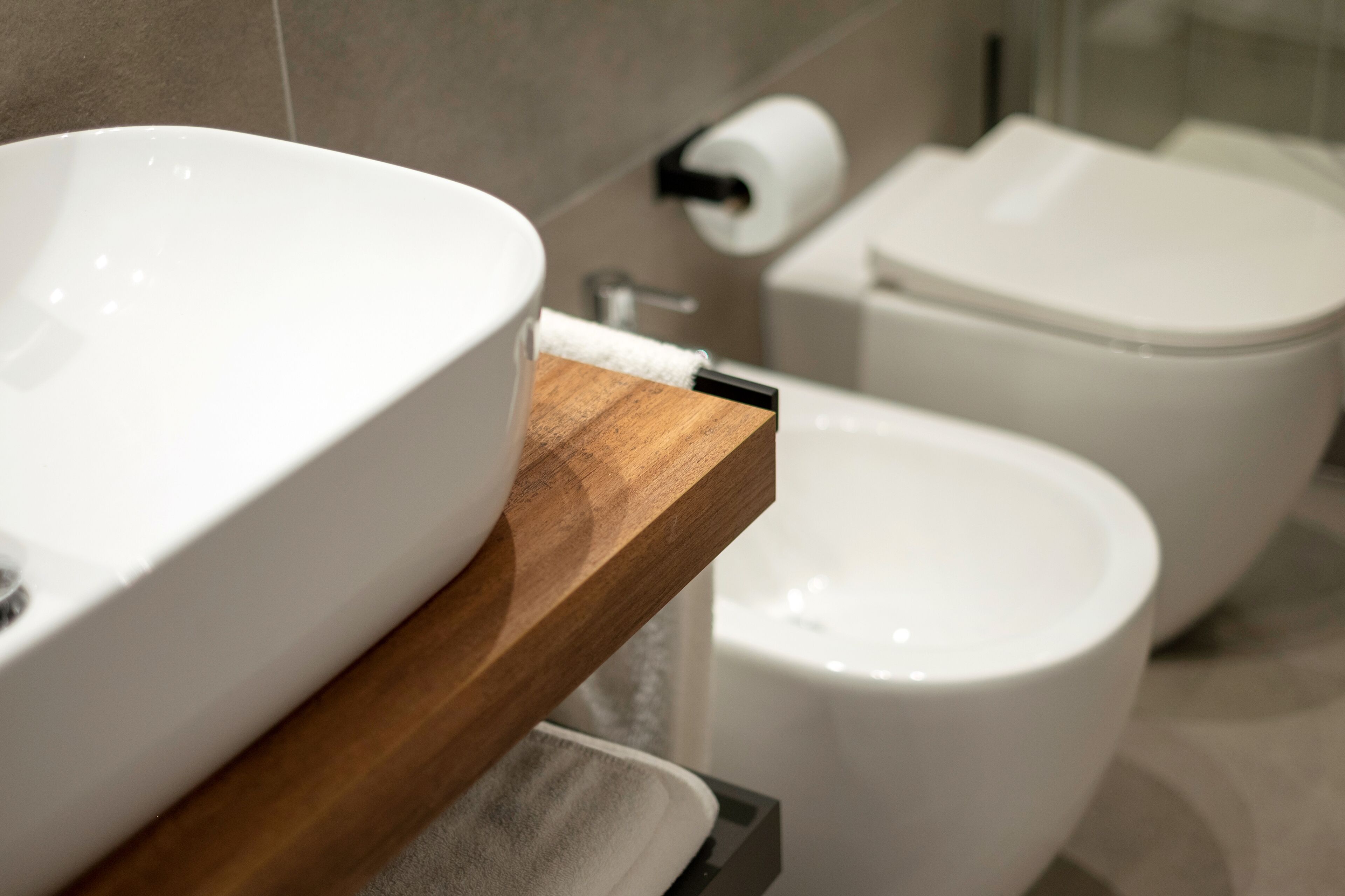 A modern bathroom with a white sink, wooden countertop, and a toilet.