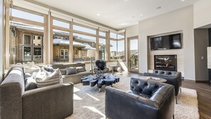Un salón amplio con ventanas grandes, chimenea y muebles modernos.