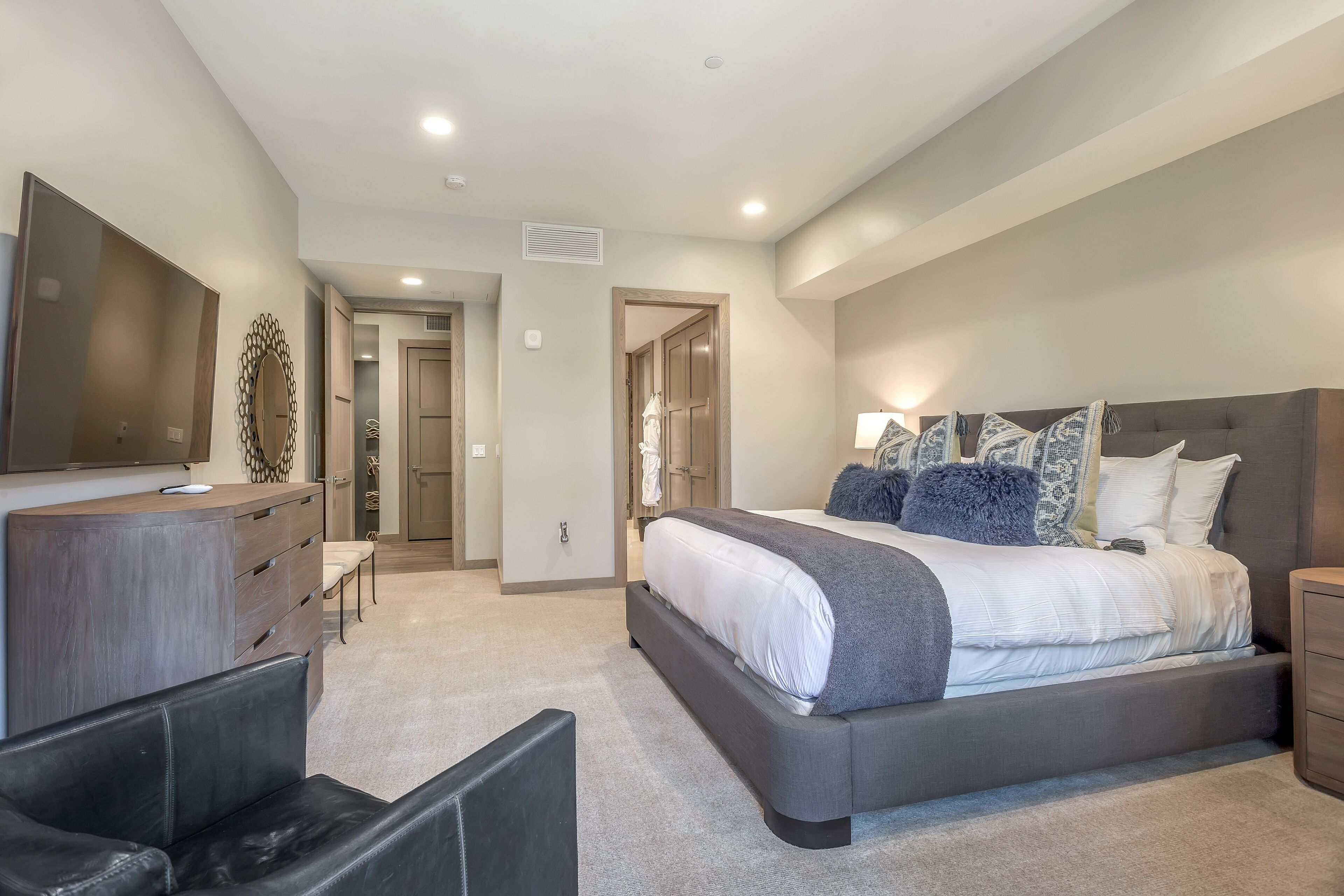 Une chambre moderne avec un grand lit, une commode, un téléviseur et un coin salon.