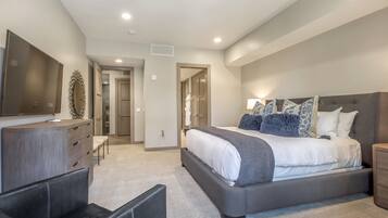 Une chambre moderne avec un grand lit, une commode, un téléviseur et un coin salon.
