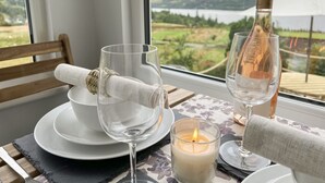 A table set with a candle, a wine bottle, and a glass with a rolled napkin. - Ciaran Cottage (Aberfeldy)