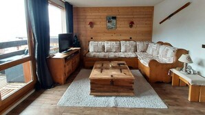 A cozy living room with a wooden sofa, a coffee table, and a TV on a wooden cabinet.