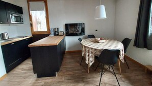 A compact kitchen with a microwave, toaster, and coffee maker. There's a dining area with a table and chairs, and a TV on the wall.