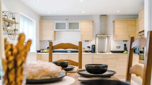 Een moderne keuken met houten kasten, een centraal eiland en een eethoek met een tafel voor twee.