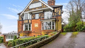 A two-story house with a steeply pitched roof, dormer windows, and a brick facade. - Stylish 1-bed Apartment - Heart of Tunbridge Wells (Royal Tunbridge Wells)