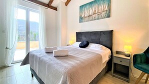A bedroom with a bed, a nightstand, a chair, a painting, and a view through a window. - Villa Vinka (Vrgorac)