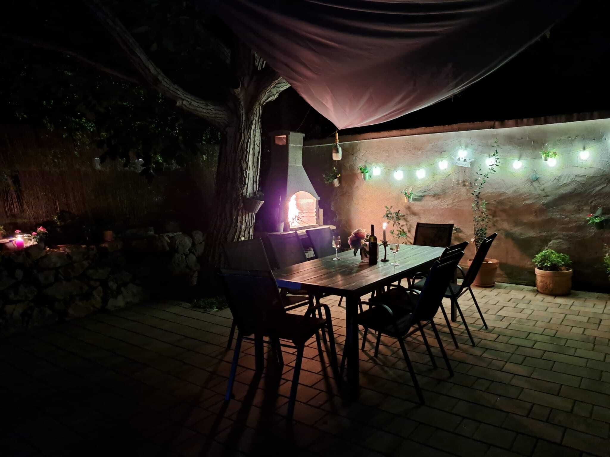 An outdoor dining area with a brick wall, hanging plants, and string lights.