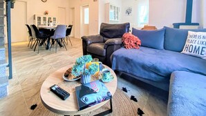A modern living room with a sofa, coffee table, and a dining area in the background. - Villa Vinka (Vrgorac)