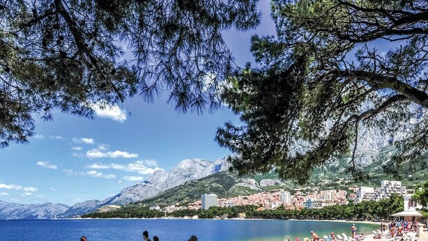 A beach with people sunbathing and walking, a clear sky, and mountains in the background. - Villa Vinka (Vrgorac)