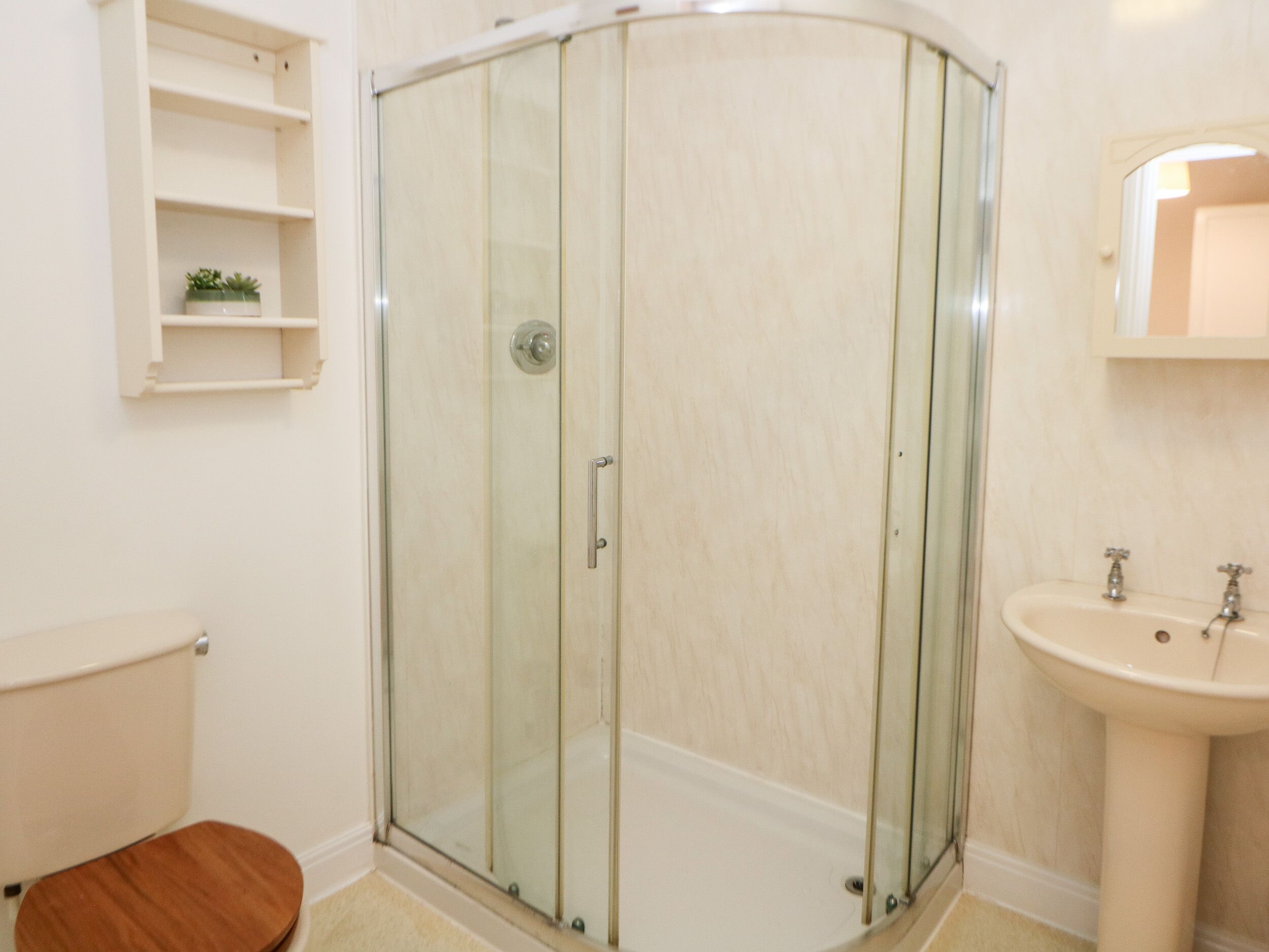 Un baño con cabina de ducha de vidrio, inodoro y lavamanos.