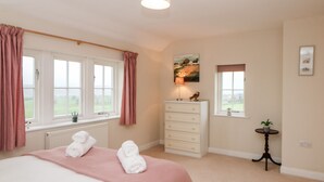 A bedroom with a bed, a dresser, a window, and a small table with a plant. - Lower Cowden Farm (Bakewell)
