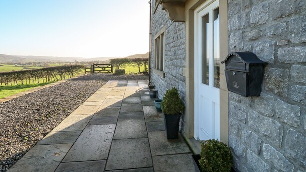 A stone building with a paved entrance, a mailbox, and a view of a rural landscape. - Lower Cowden Farm (Bakewell)