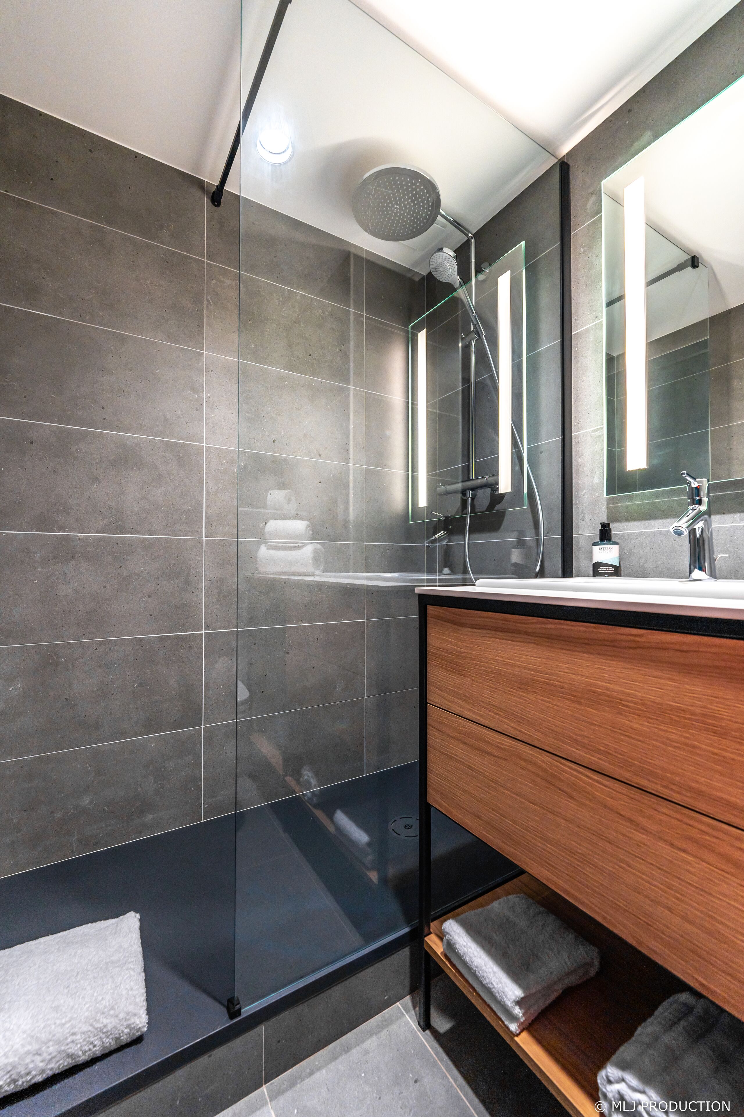 A modern bathroom with a glass-enclosed shower, a wooden vanity, and a large mirror.