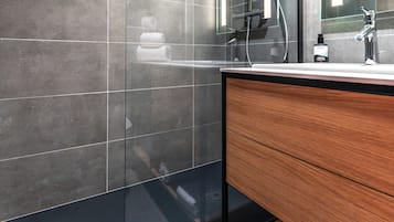 A modern bathroom with a glass-enclosed shower, a wooden vanity, and a large mirror.
