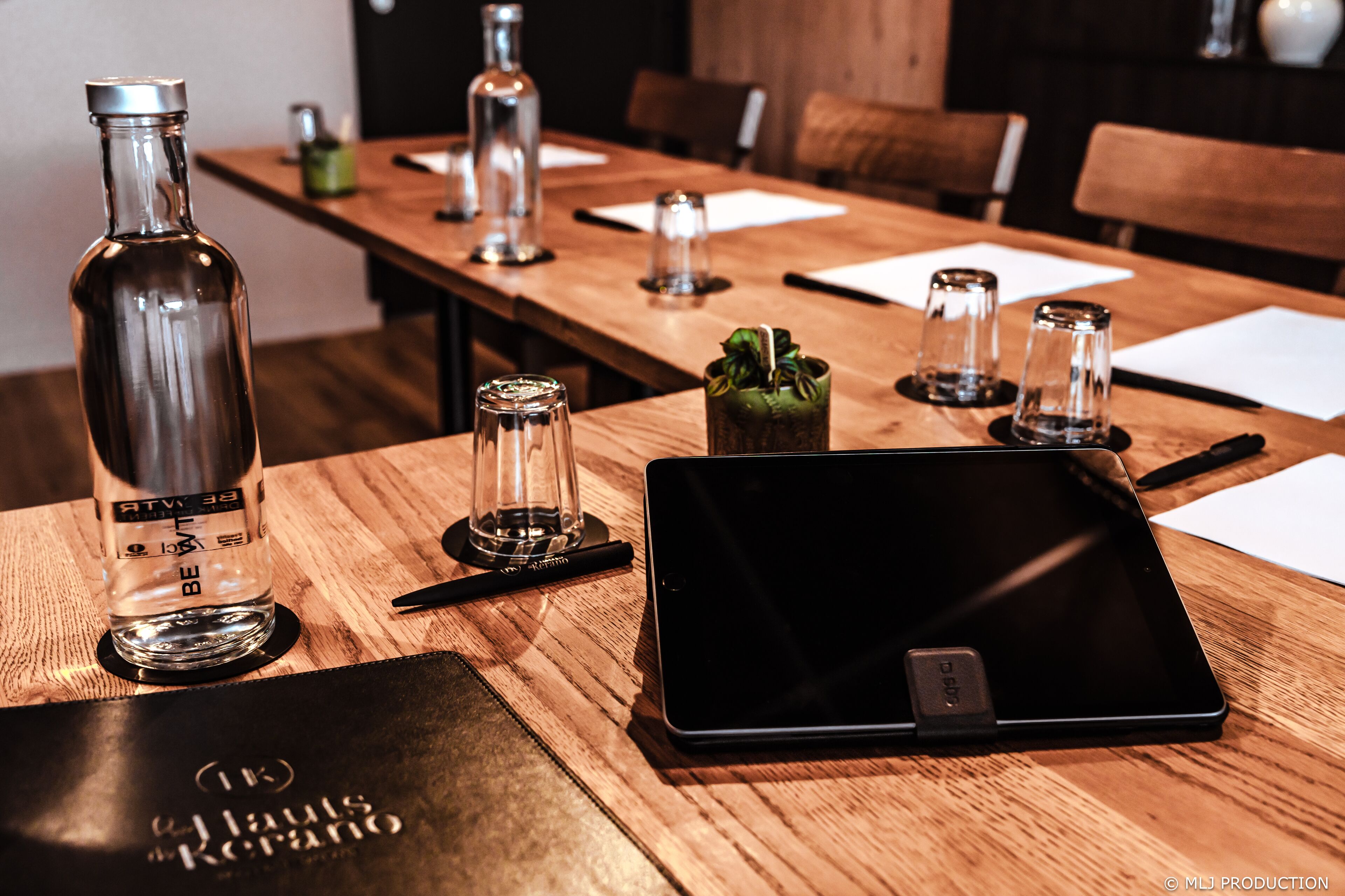 A wooden table with a tablet, a bottle, and salt and pepper shakers.