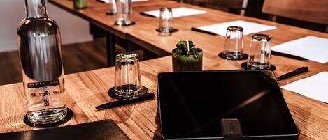 A wooden table with a tablet, a bottle, and salt and pepper shakers.