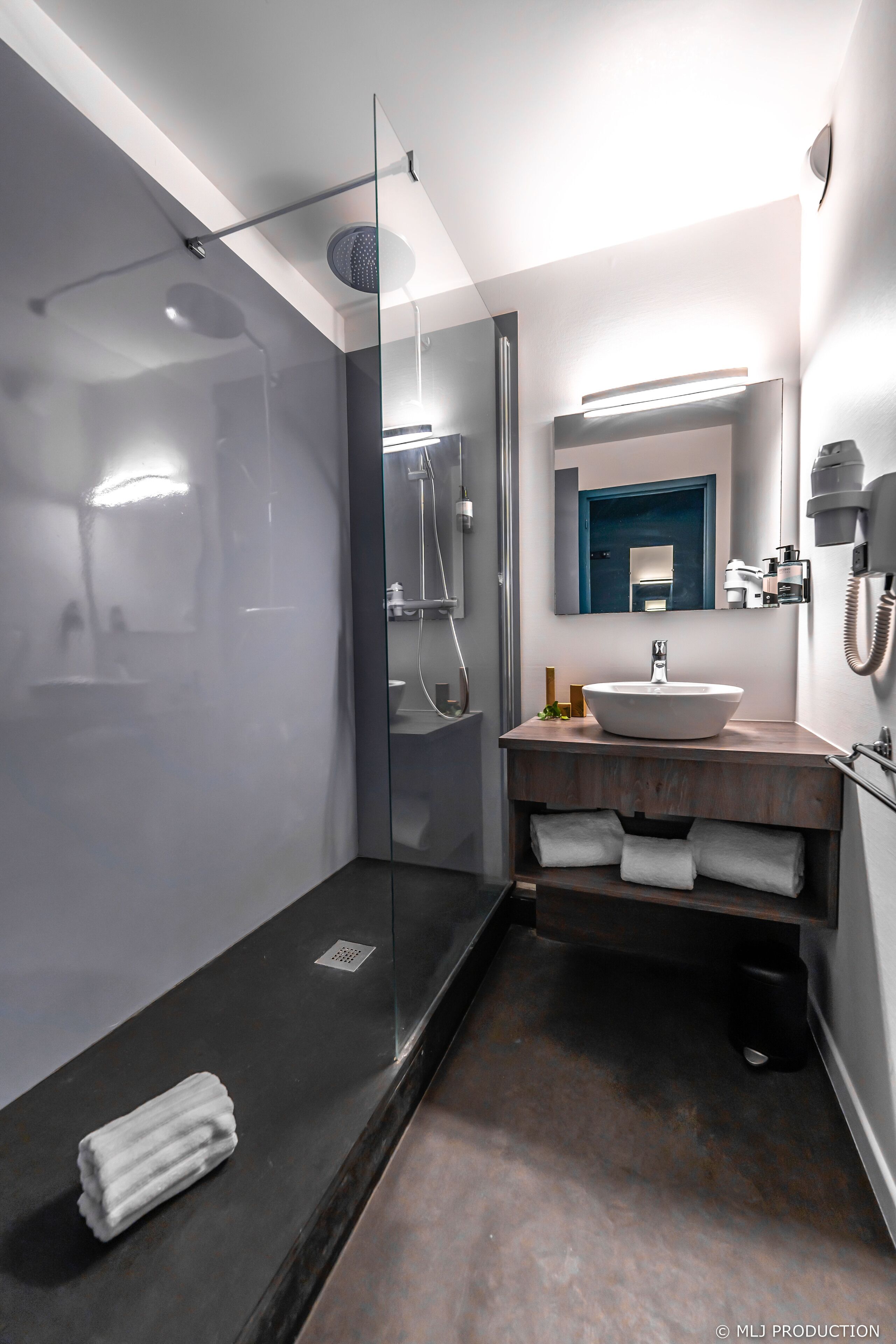 A modern bathroom with a glass-enclosed shower, a round sink, and a mirror above the vanity.