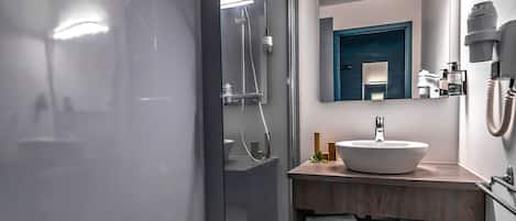 A modern bathroom with a glass-enclosed shower, a round sink, and a mirror above the vanity.