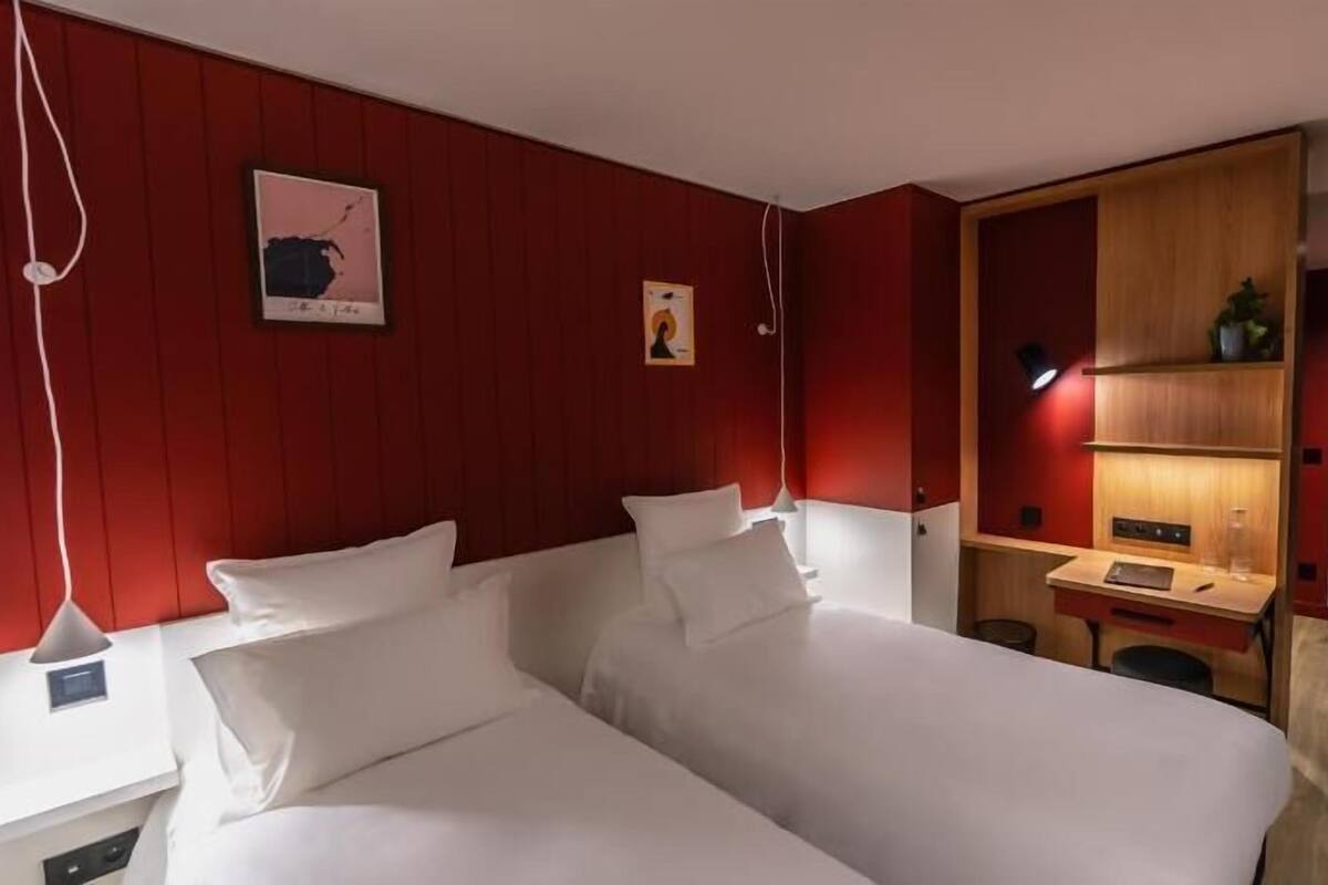 Ein Hotelzimmer mit zwei Betten, einem Schreibtisch, einem Stuhl, einem Kleiderschrank und einer Tür.