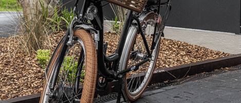 A bicycle with a wicker basket parked on a paved area.