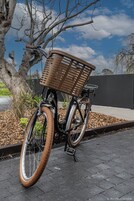 A bicycle with a wicker basket parked on a paved area.