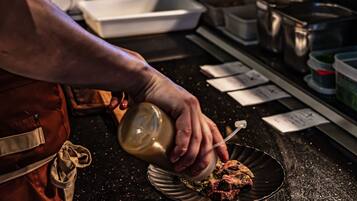 A person in an apron preparing food in a kitchen with various cooking utensils and containers.