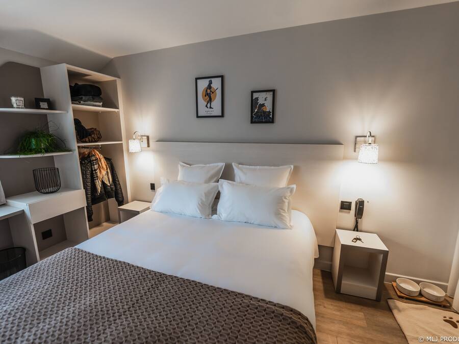 Une chambre à coucher bien rangée, avec un grand lit, une armoire intégrée et une table de chevet avec une lampe.