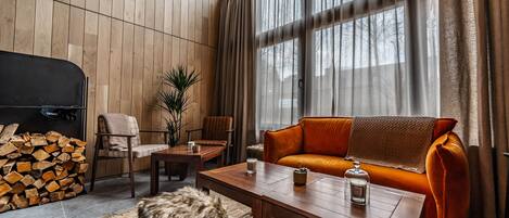 Un salon chaleureux avec un mur en bois, un canapé, des fauteuils, une table basse et une cheminée.