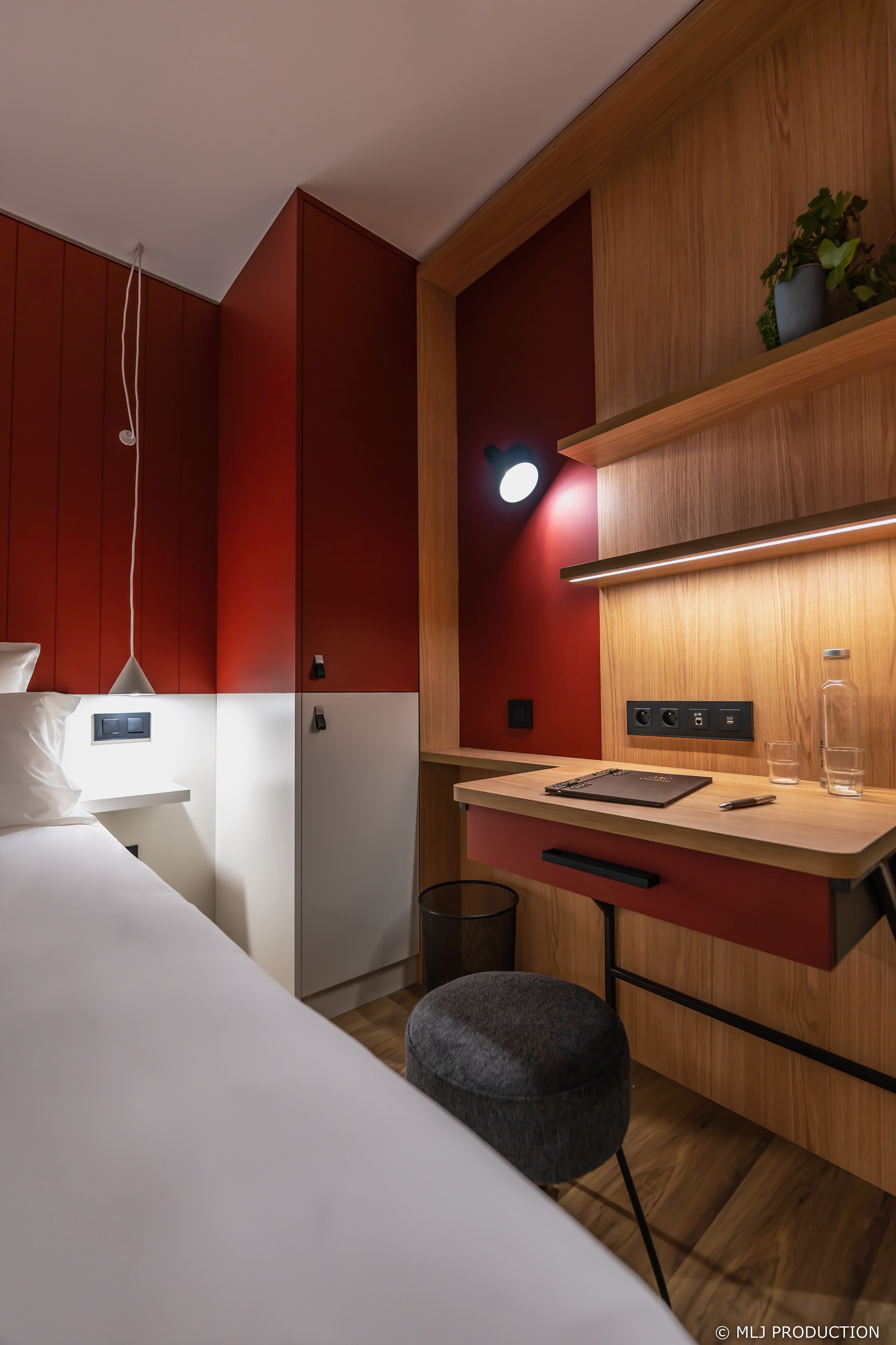 Un dormitorio moderno con cama, mesita de noche y zona de escritorio con silla.