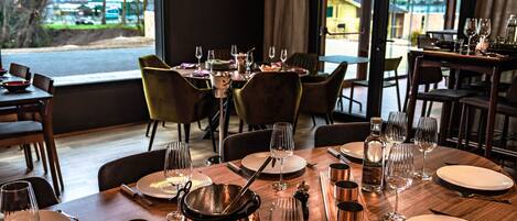 A dining area with tables set for a meal, including plates, cutlery, and wine glasses.