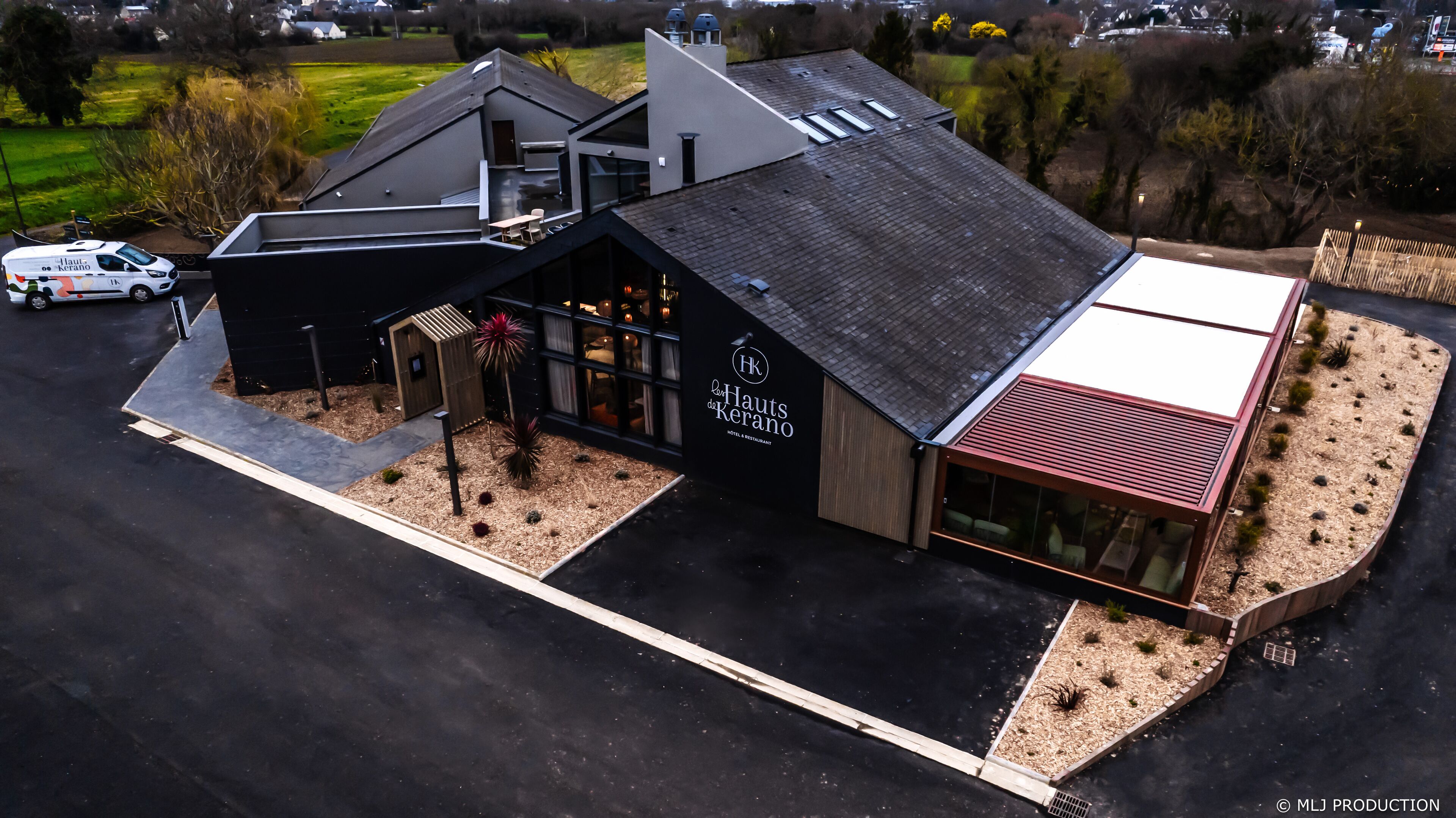 A modern hotel with a flat roof, large windows, and a well-maintained garden area.