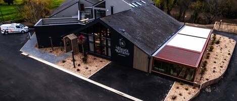 A modern hotel with a flat roof, large windows, and a well-maintained garden area.