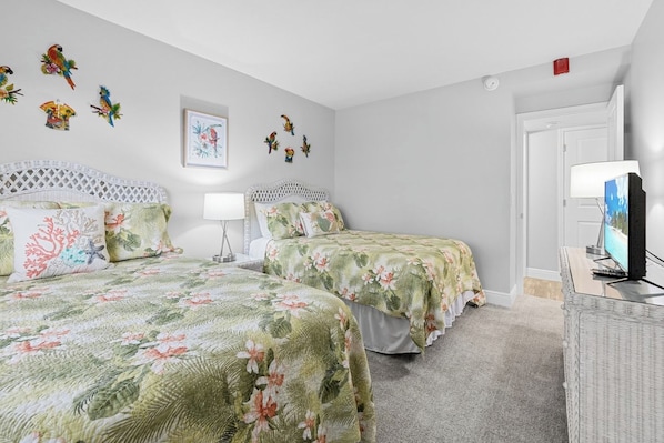 A hotel room with two beds, a television, and wall decorations.