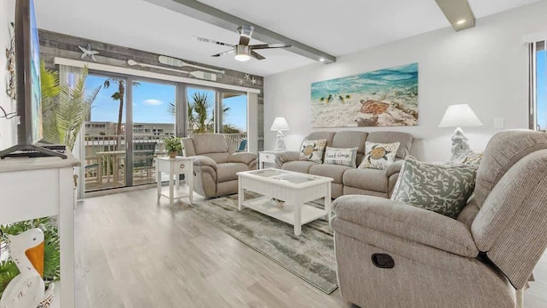 A modern living room with a sofa, coffee table, and a painting of a beach scene.