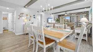 A modern living room with a dining area, white furniture, and decorative wall art.