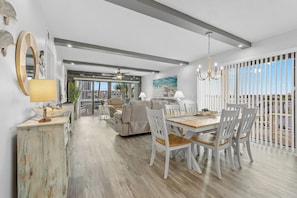 A spacious living area with a dining table and chairs, a sofa, and a view of the outdoors.