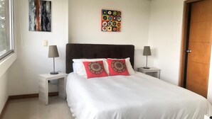 Une chambre bien rangée, avec un grand lit, deux tables de chevet et une fenêtre.